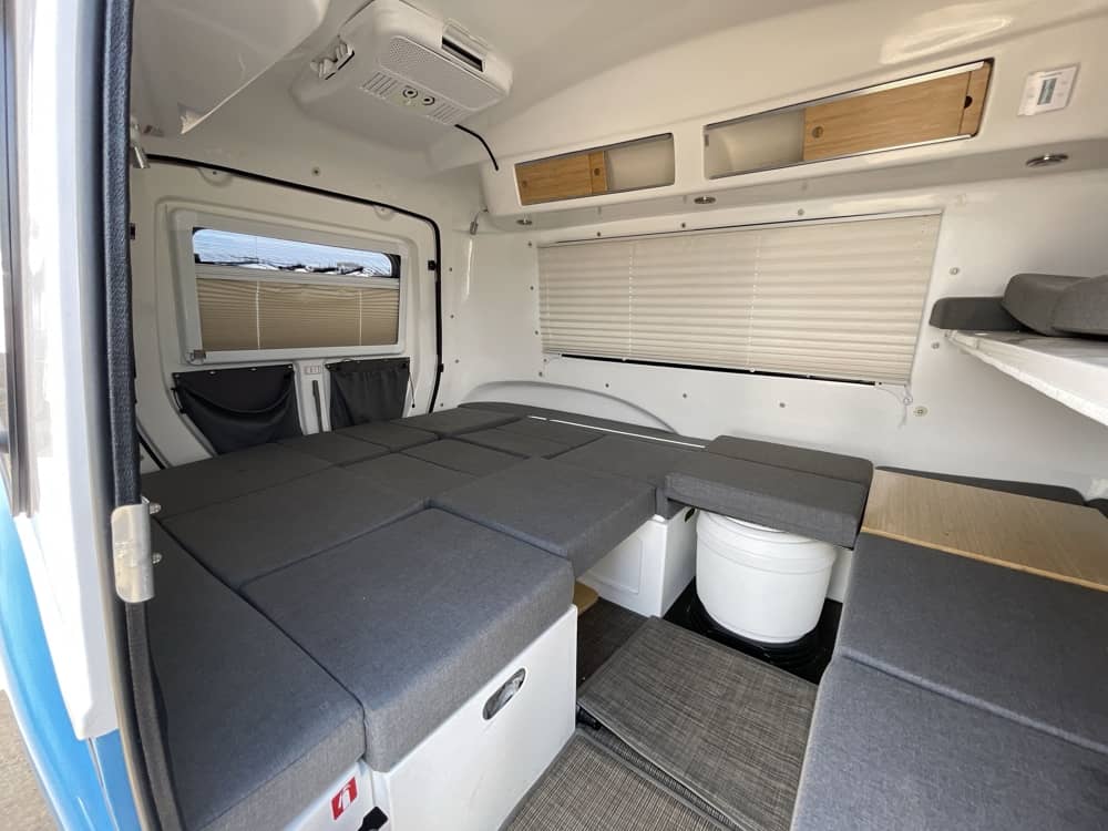 Interior — alternate layout showing living space, portable toilet, and shelf storage